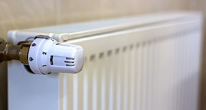 close up of a white radiator with a heating valve showing numbers one to five for temperature settings