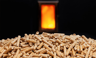 wood pellets stacked in front of a warm glowing stove for efficient heating solutions